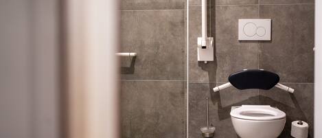 A modern bathroom with a toilet, bidet, and a hand dryer.