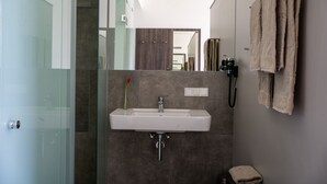Un baño moderno con cabina de ducha de vidrio, un lavabo blanco y un perchero para toallas.