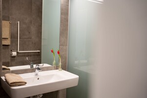 A bathroom with a white sink, a mirror, and a towel rack.