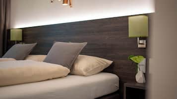 A modern hotel room with a large bed, two bedside lamps, and a small bedside table with a plant.