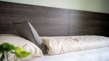 Una cama bien hecha con tablero de madera y dos almohadas.