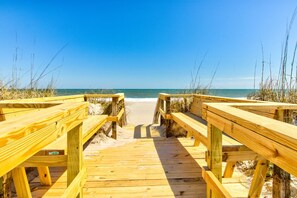 A wooden boardwalk leading to a beach with clear skies.