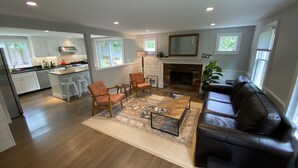 A spacious living area with a fireplace, a black leather sofa, and a coffee table. - Well Appointed Modern 3 bedroom Cape House, Fully Renovated in 2020! (Harwich)