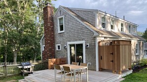 A two-story house with a deck, a brick chimney, and a covered patio area. - Well Appointed Modern 3 bedroom Cape House, Fully Renovated in 2020! (Harwich)