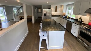 A modern kitchen with white cabinets, a granite countertop, and stainless steel appliances. - Well Appointed Modern 3 bedroom Cape House, Fully Renovated in 2020! (Harwich)