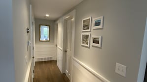 A hallway with wooden flooring, white walls, and recessed lighting. - Well Appointed Modern 3 bedroom Cape House, Fully Renovated in 2020! (Harwich)