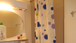 A bathroom with a white sink, a mirror above it, and a shower curtain with a polka dot pattern.