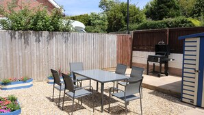 An outdoor patio with a table and chairs, surrounded by gravel and flower planters.