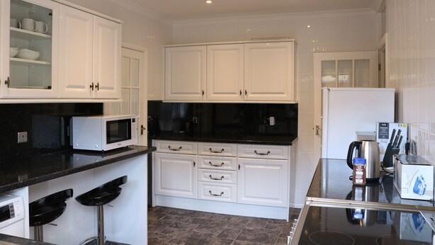 A modern kitchen with white cabinets, a black countertop, and a stainless steel refrigerator.