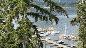 A marina with boats docked, surrounded by trees and a body of water. - Shore 2 Please - Lower Unit,BRIGHT/Mountain views (Port Renfrew)