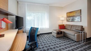 A hotel room with a desk, chair, sofa, TV, lamp, and artwork on the wall. - TownePlace Suites by Marriott Niceville Eglin AFB Area (Niceville)