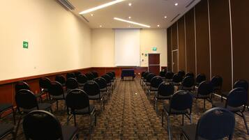 A conference room with rows of chairs, a projector screen, and a podium.