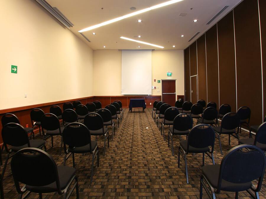 A conference room with rows of chairs, a projector screen, and a podium.