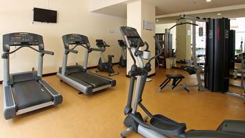 Un gimnasio con cintas de correr, elípticas y equipo de levantamiento de pesas.