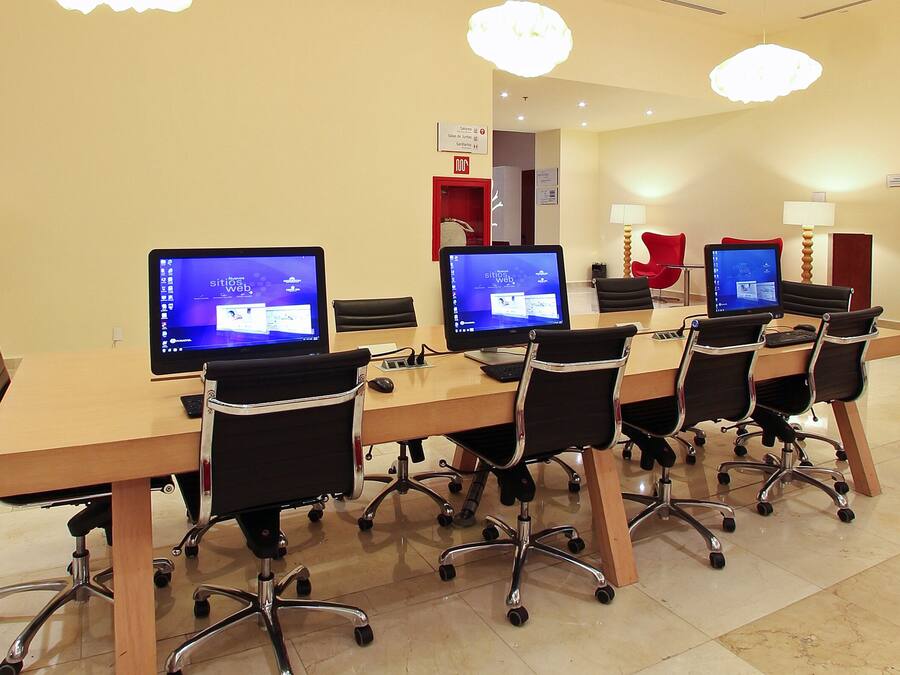 A conference room with a long table, multiple chairs, and several computer monitors.
