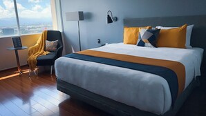 Une chambre d’hôtel avec un grand lit, une chaise, une petite table et une vue sur la ville par une grande fenêtre.