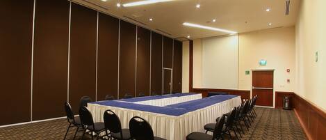 A conference room with a long table, chairs, and a carpeted floor.