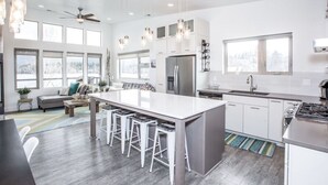Una cocina moderna con una isla grande, taburetes de bar y un área de comedor con sofá y mesa de centro.