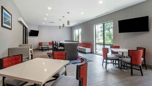 A modern dining area with tables and chairs, a counter, and a TV mounted on the wall. - Comfort Inn & Suites Olive Branch Old Towne (Olive Branch)