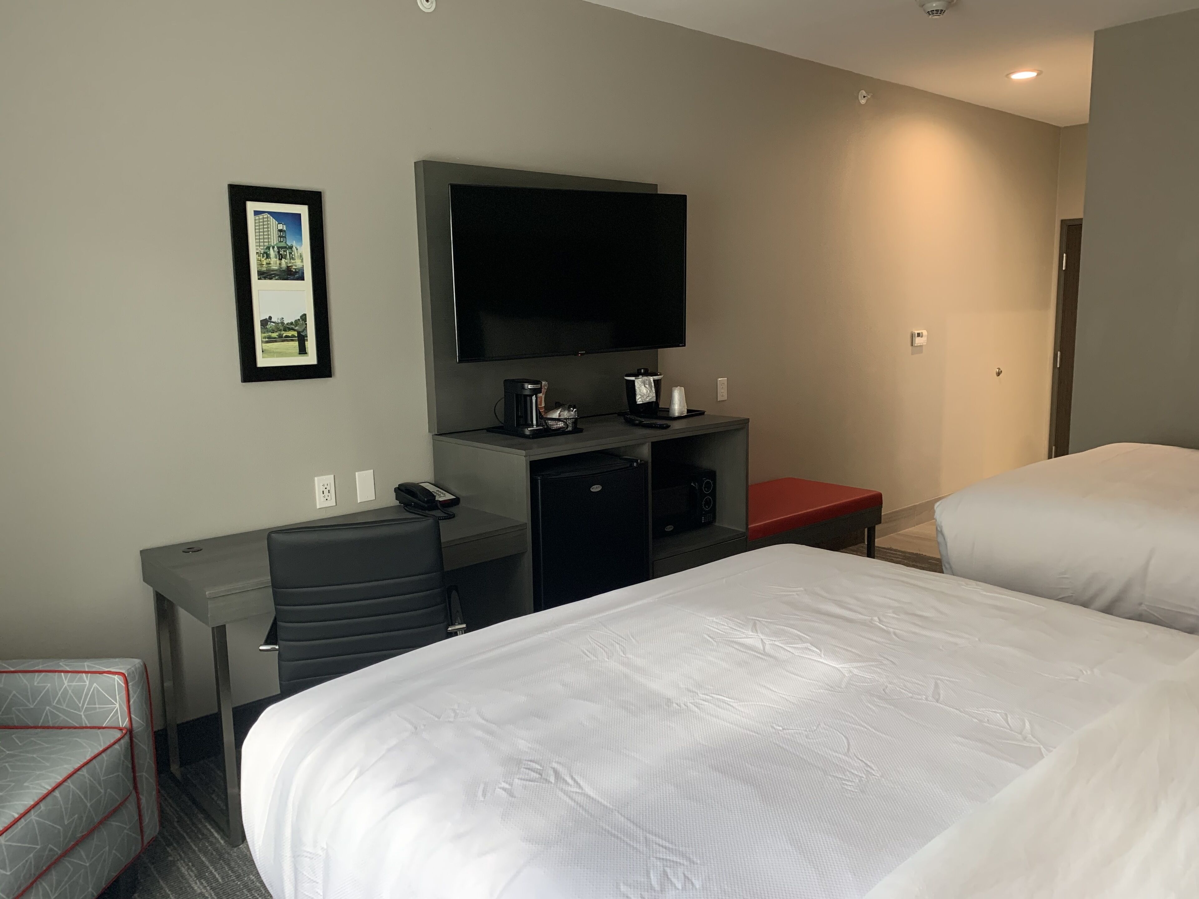 A hotel room with a bed, a desk with a computer, a television, and a coffee maker.