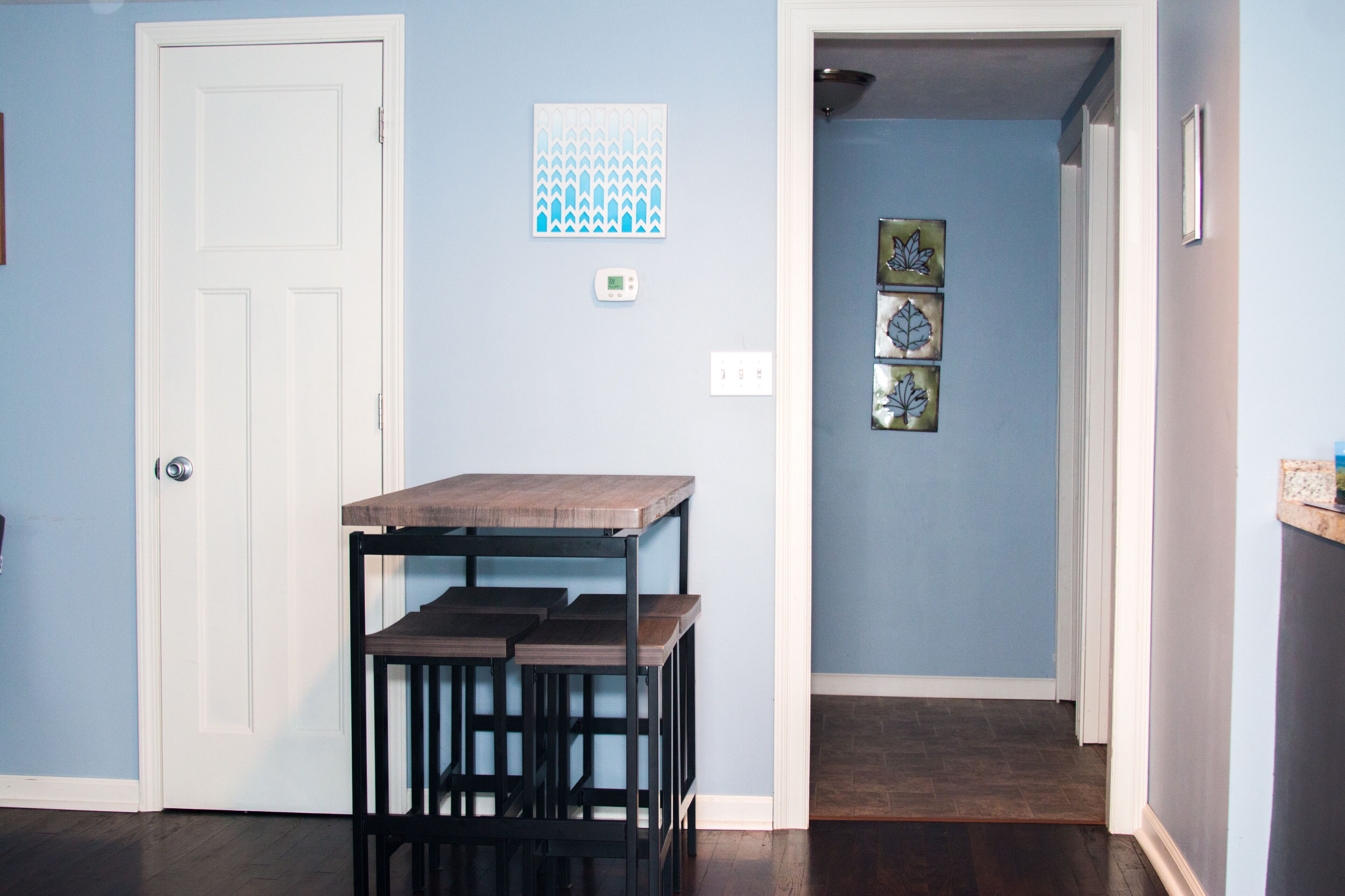 Un pasillo con una mesa y sillas de madera, una puerta blanca y decoración en la pared.