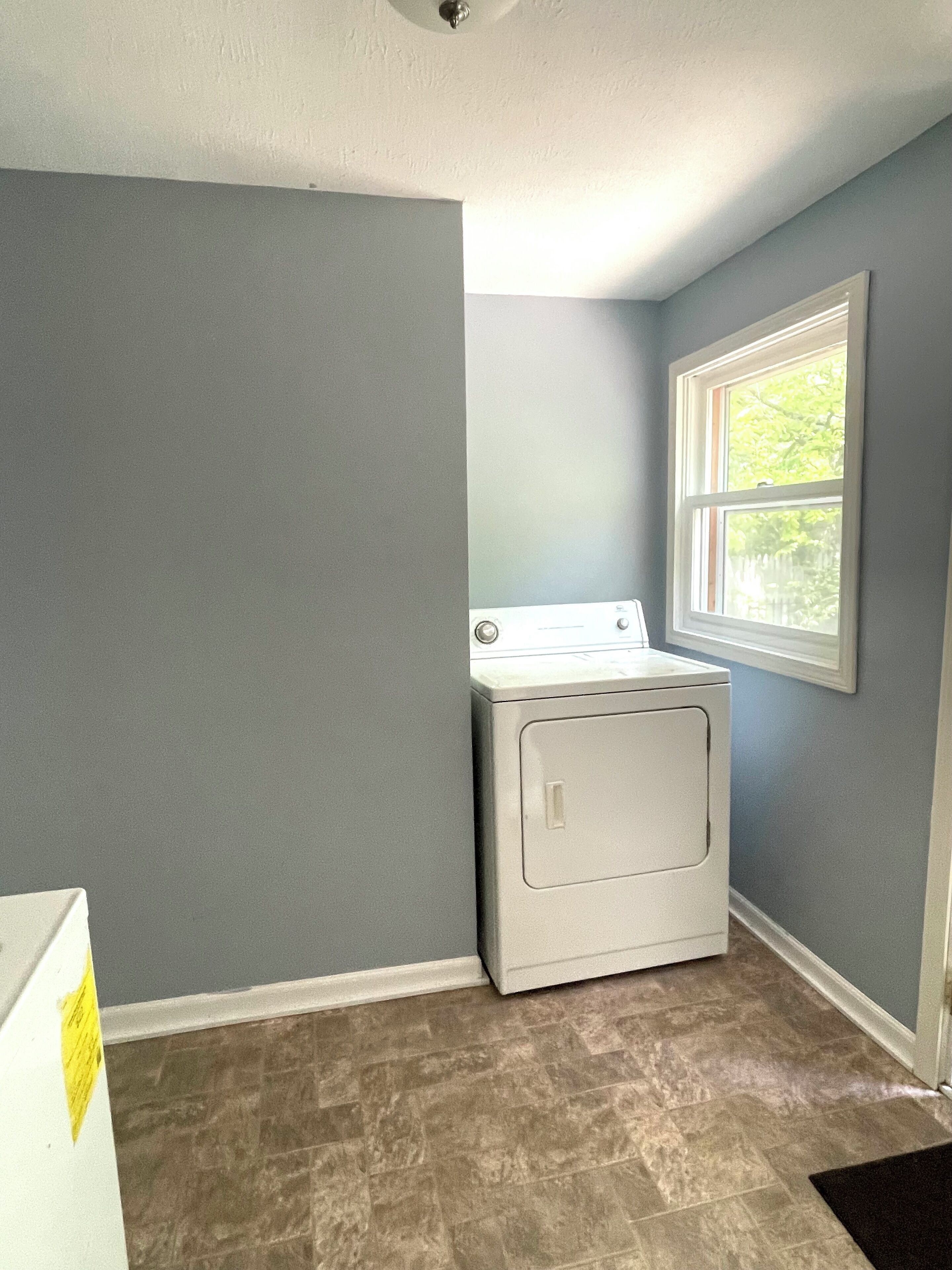 A laundry room with a washing machine, a window, and a door.