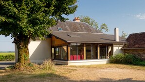 A house with a large tree in front, a covered porch, and a view of the countryside.