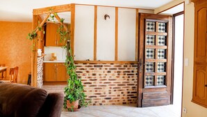 A cozy room with a brick wall, wooden door, and a small plant.