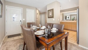 Un comedor con una mesa de madera dispuesta para cuatro personas, rodeada de sillas marrones.