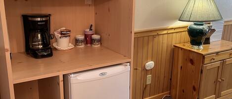 A compact kitchenette with a microwave, coffee maker, and small refrigerator. A deer head is mounted on the wall above the counter.