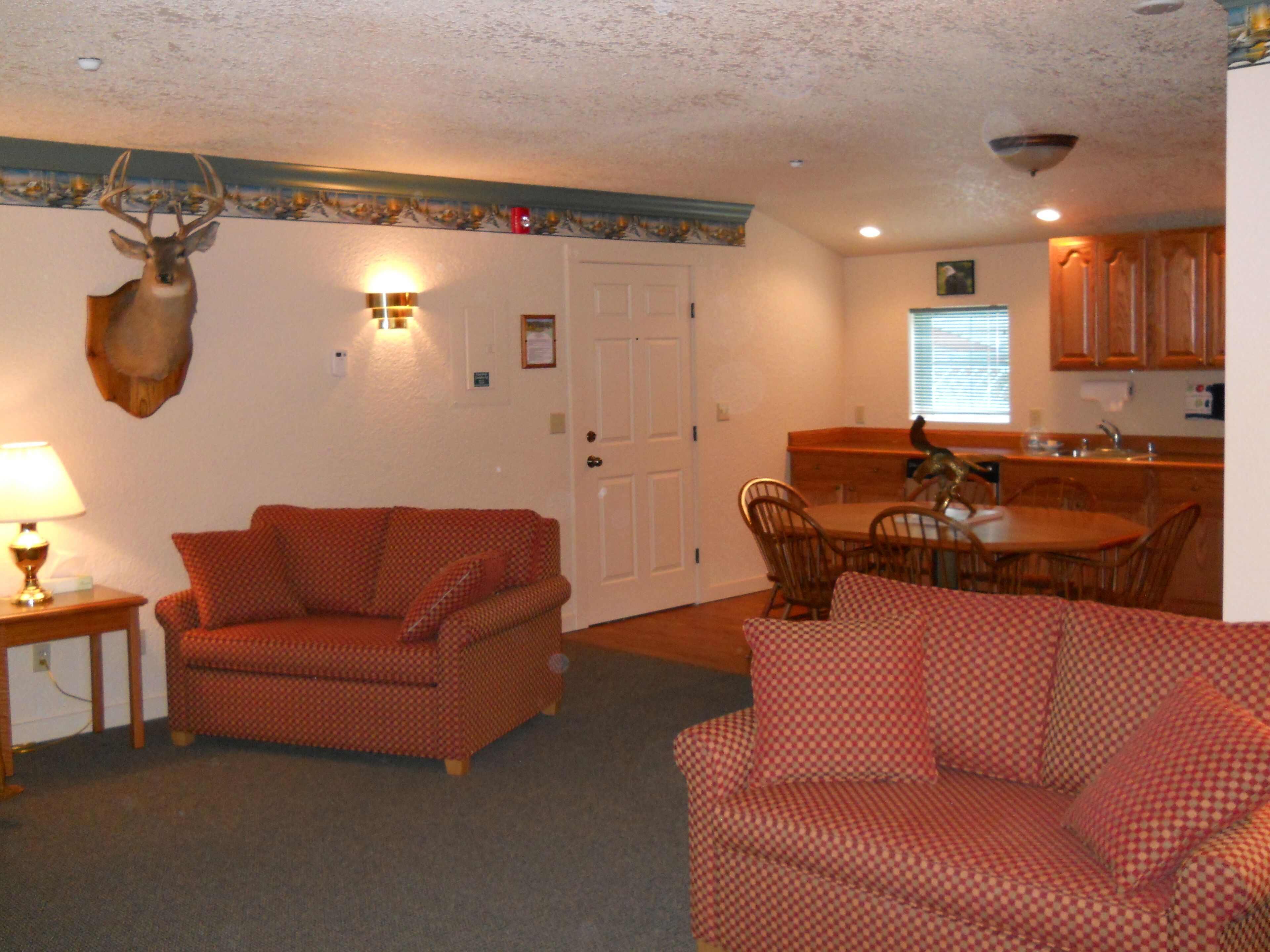 A living room with a fireplace, a dining area with a wooden table and chairs, and a kitchen with wooden cabinets.