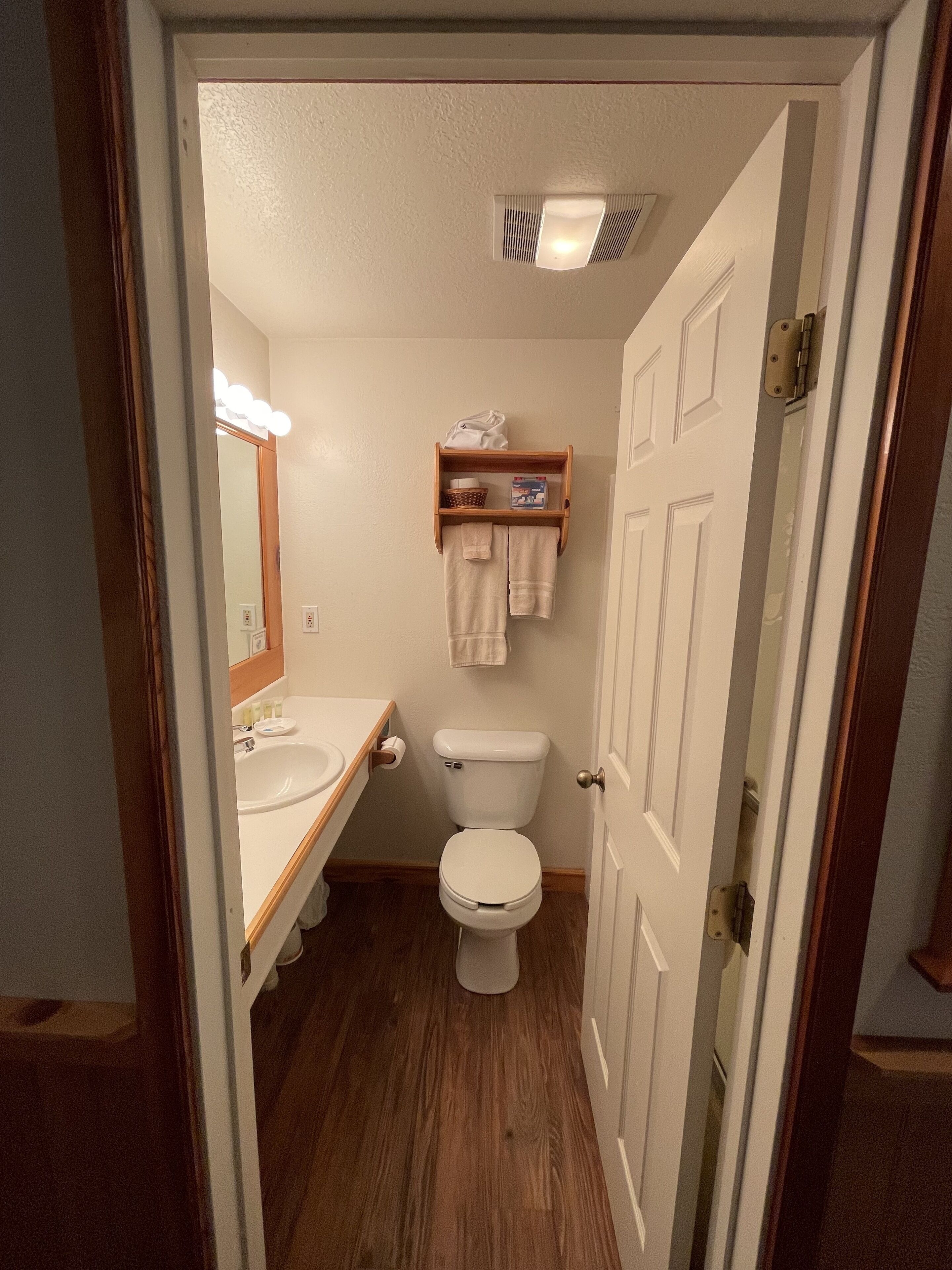 Ein kleines Badezimmer mit Toilette, Waschbecken und einem beleuchteten Spiegel.