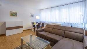 Ein modernes Wohnzimmer mit einer Couch, einem Glastisch und einem Essbereich mit Stühlen und einem Tisch.