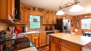 A wooden cabin-style kitchen with a stove, sink, and refrigerator.