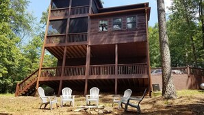A multi-level wooden cabin with a balcony, surrounded by trees.