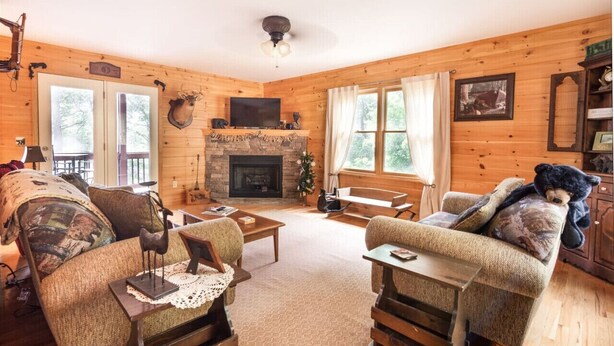 A cozy log cabin interior with a fireplace, wooden walls, and comfortable seating.