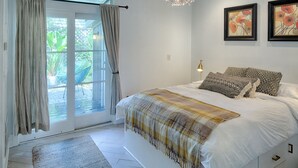 A bedroom with a large bed, a chandelier, and two framed artworks on the wall. - Romantic Cottage in Savannah's Beautiful Historic District! (Savannah)