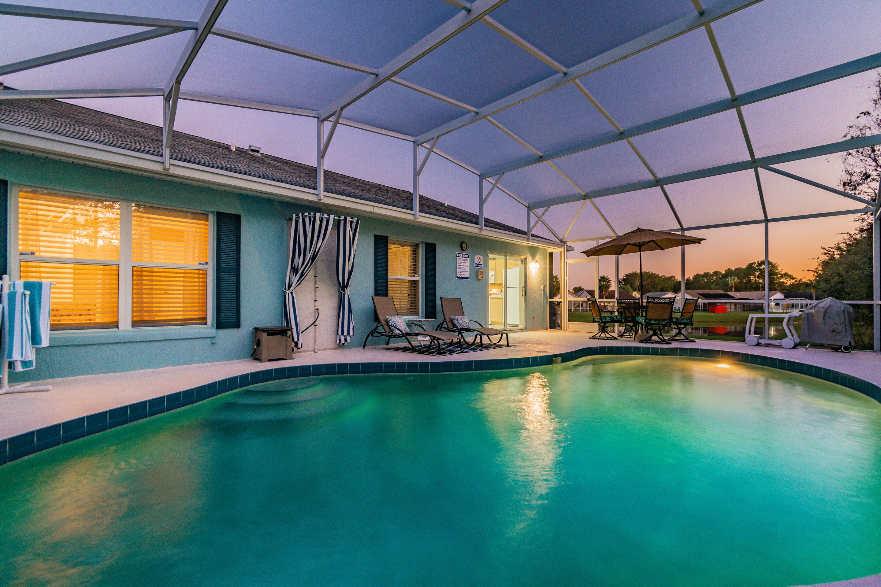 A swimming pool with lounge chairs and umbrellas, surrounded by a covered patio area.