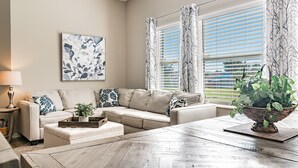 A living room with a beige sofa, a coffee table, and a potted plant. - Near Theme Parks! In-Ground 3 BR Pool Home, Sleeps 7, Total Privacy! (Kissimmee)