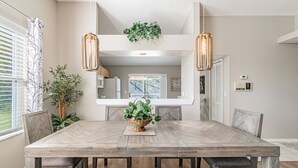 A dining area with a large wooden table, two pendant lights, and a potted plant. - Near Theme Parks! In-Ground 3 BR Pool Home, Sleeps 7, Total Privacy! (Kissimmee)