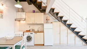 A compact kitchen with a washing machine, a dining area with a table and chairs, and a staircase. - GuestHost - Functional 35sqm apartment, well furnished, that can accommodate up to 4 people. Located on the third floor, without lift, of an historic Florentine building few steps away from Palazzo Medici Riccardi and 3 minutes on foot from the Duomo. Th (Firenze)