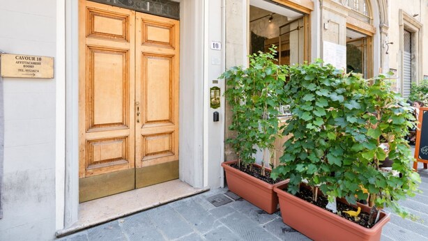A hotel entrance with double wooden doors, a sign indicating room number 10, and potted plants outside. - GuestHost - Functional 35sqm apartment, well furnished, that can accommodate up to 4 people. Located on the third floor, without lift, of an historic Florentine building few steps away from Palazzo Medici Riccardi and 3 minutes on foot from the Duomo. Th (Firenze)