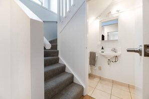 A staircase leading to a bathroom with a white sink and a mirror above it.