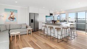 Una cocina moderna con una isla central, taburetes de bar, un refrigerador y un ventanal grande.