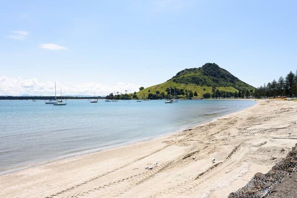 Una spiaggia con barche, una riva sabbiosa e una collina sullo sfondo.