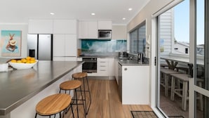 Una cocina moderna con una isla central, armarios blancos y un ventanal grande.