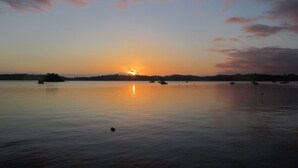 Ruhiges Gewässer mit Booten und einem Sonnenuntergang.