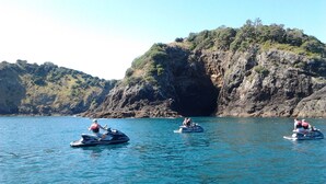 Drei Jetskis auf ruhigem Wasser, im Hintergrund felsige Klippen.