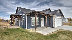 A two-story house with a garage, a covered porch, and a well-maintained lawn. - Blue Bear Bungalow - Pool Access and only One Block From The Lake! (Garden City)