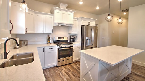 A modern kitchen with white cabinetry, stainless steel appliances, and pendant lighting. - Blue Bear Bungalow - Pool Access and only One Block From The Lake! (Garden City)
